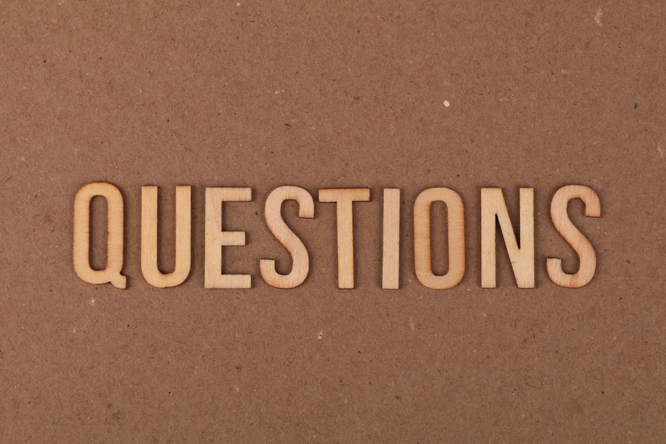Wooden letters spelling the word "QUESTIONS" on a cardboard background, providing a neutral copyspace.